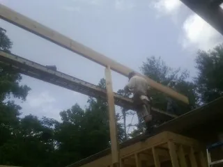 Carpenter setting a ridge beam over a new addition frame — Ice Dam Removal by Roofing Brothers in Medford