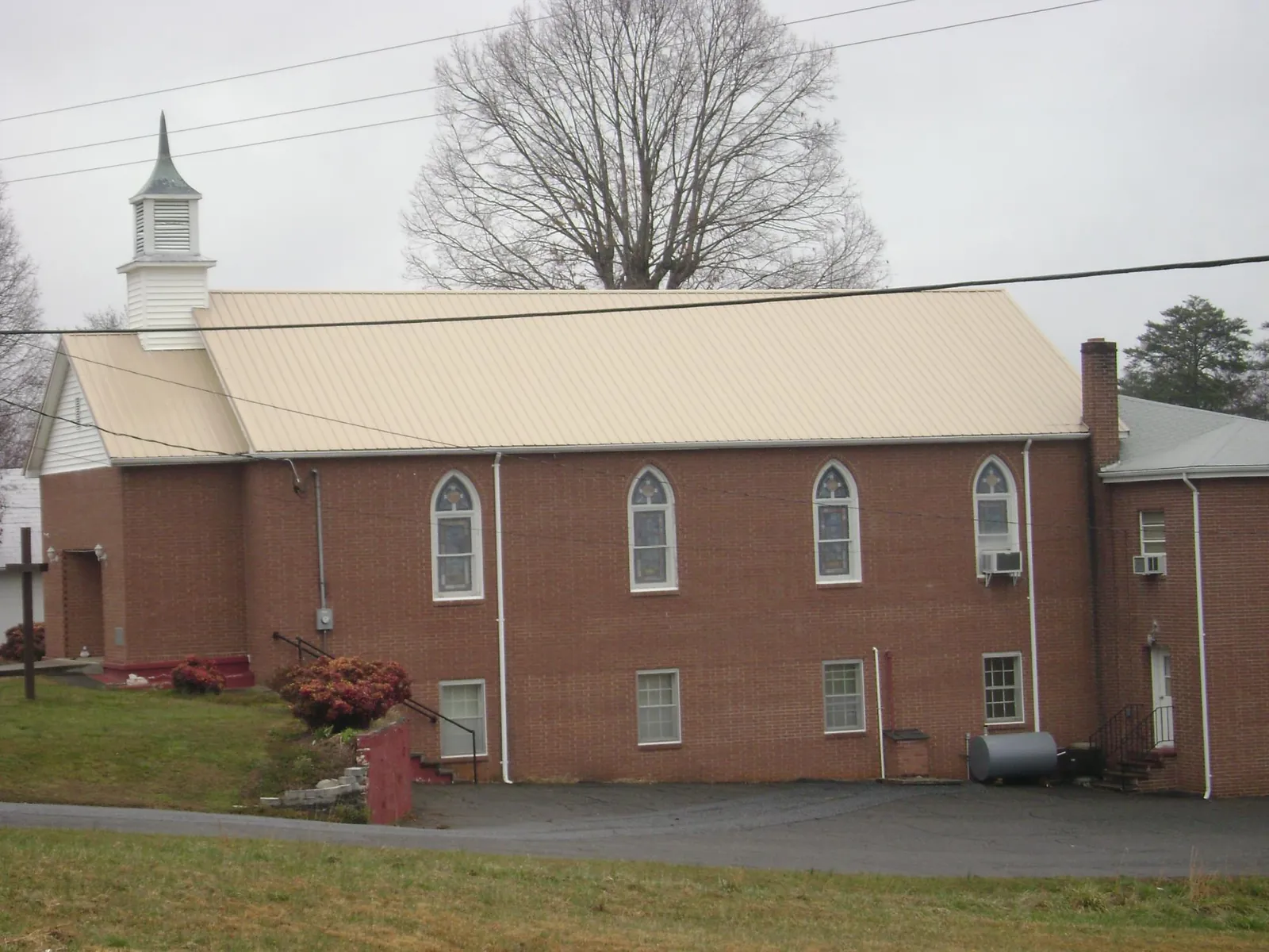 New tan metal roof on a brick church with a white steeple in Medford