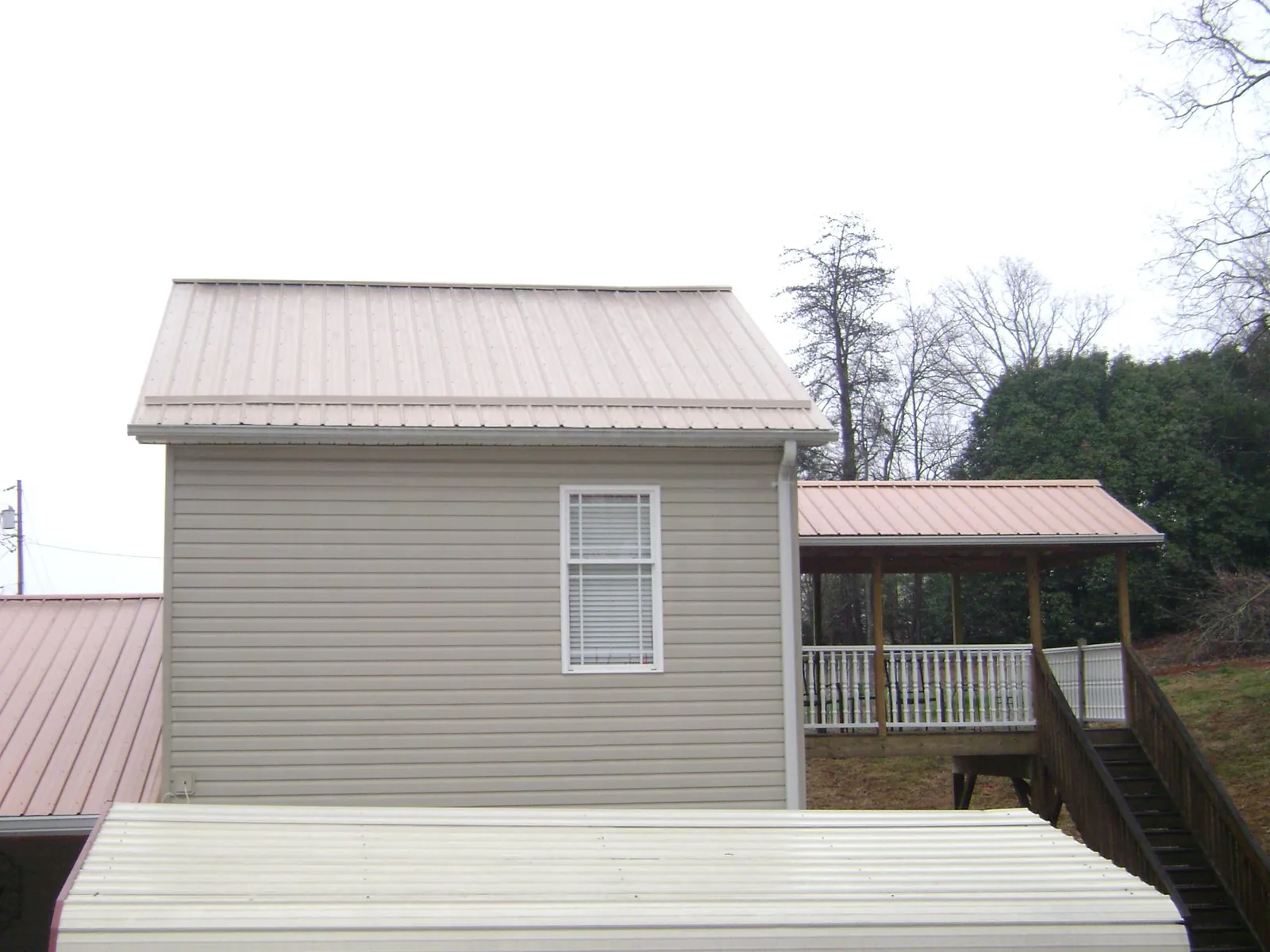 Tan metal roofs on a two story addition and attached porch, from a Roof Replacement job in Medford